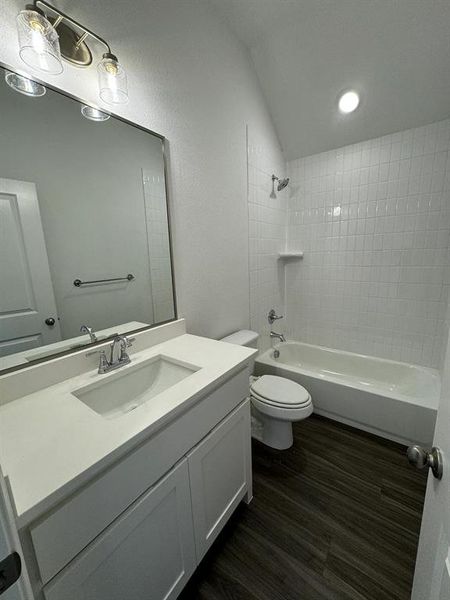 Full bathroom featuring toilet, vanity, tiled shower / bath combo, and hardwood / wood-style flooring