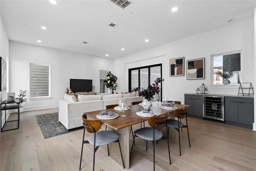 From intimate dinners to lively soirées, this open-concept space adapts with grace. Anchored by a custom dry bar and defined by a palette of soft neutrals and warm wood, the dining and living areas flow effortlessly into one another—culminating in floor-to-ceiling sliding doors that invite natural light and outdoor connection. It's a layout that supports the pace of modern living without ever feeling rushed.