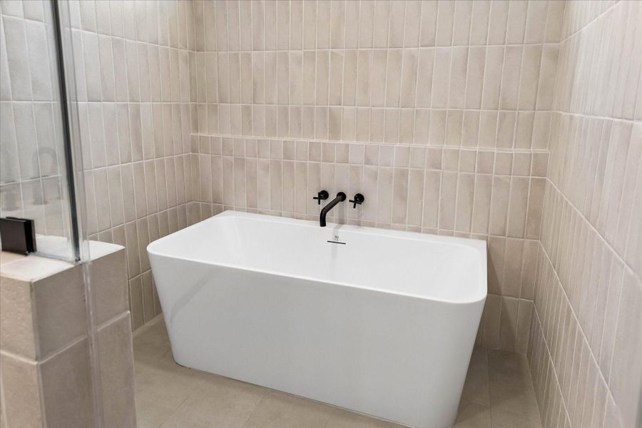 A freestanding soaking tub, oversized walk in shower, and full height tile surround create a spa inspired retreat designed for everyday luxury.