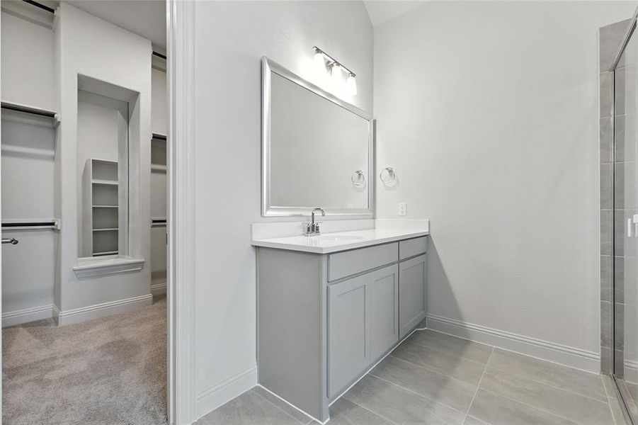 Full bath featuring a spacious closet, vanity, light tile patterned floors, and a shower with shower door