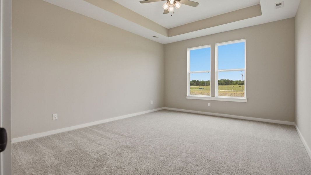 Bedroom with tray ceiling, windows, and ceiling fan Bedroom with tray ceiling, windows, and ceiling fan