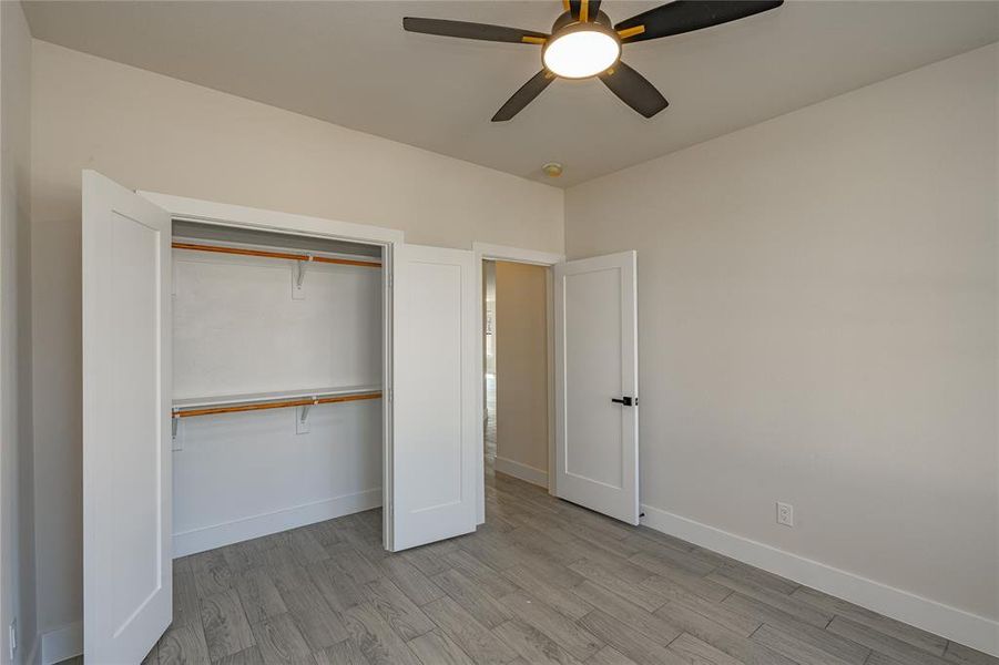 Unfurnished bedroom with light wood-type flooring, ceiling fan, and a closet