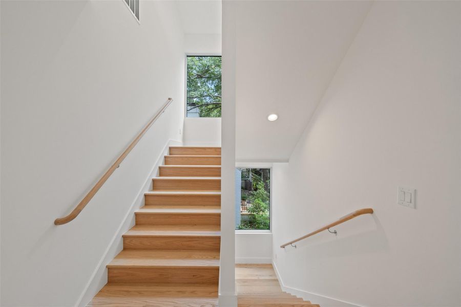 Staircase featuring plenty of natural light, recessed lighting, and wood finished floors Staircase featuring plenty of natural light, recessed lighting, and wood finished floors