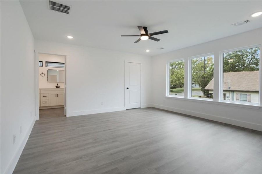 Unfurnished bedroom with hardwood / wood-style flooring, connected bathroom, and ceiling fan