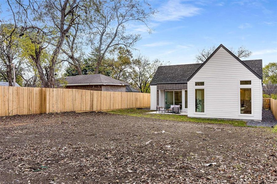Back of property with a patio, a fenced backyard, and a shingled roof