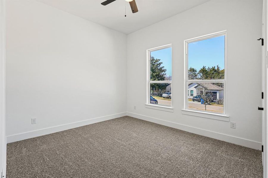 Carpeted empty room featuring a ceiling fan and baseboards