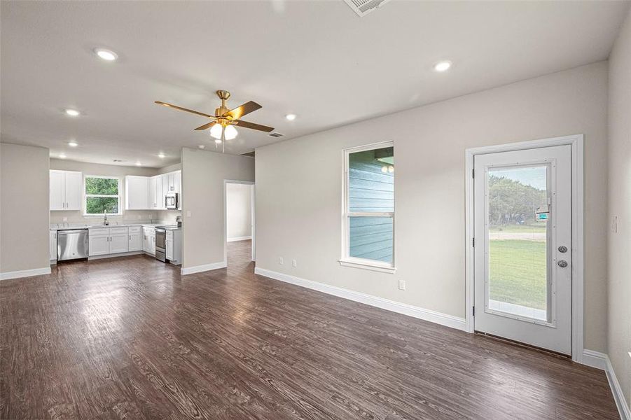 Unfurnished living room with sink, dark wood-type flooring, and ceiling fan