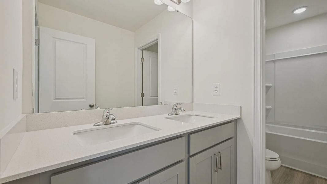 Wagener home plan secondary bathroom with dual vanities, toilet room and shower