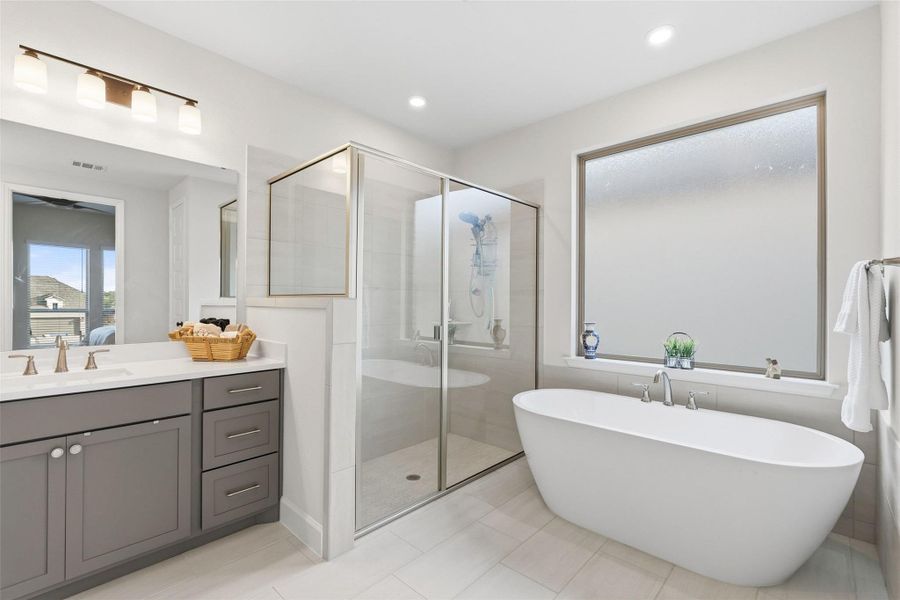 Freestanding soaking tub with polished chrome fixtures, alongside a glass-enclosed shower