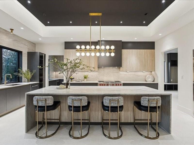 A large kitchen island with beautiful lighting and a striking granite waterfall design serves as the centerpiece of the space.