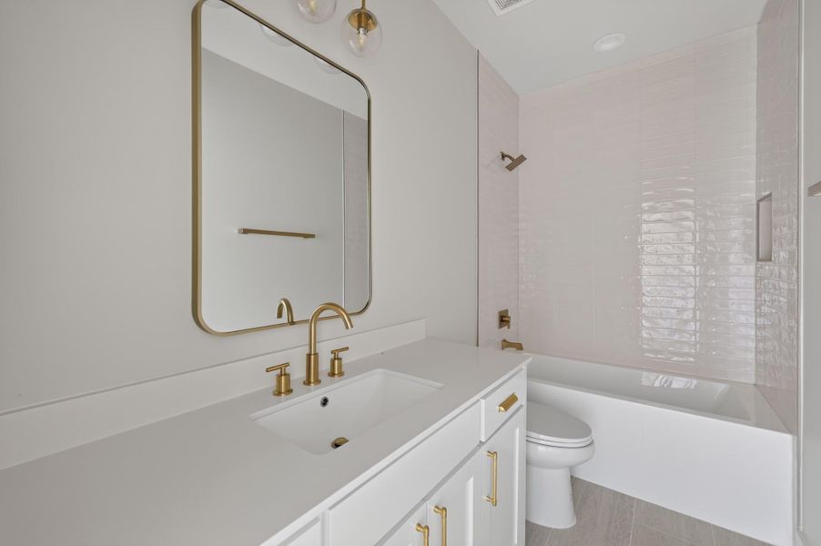 Gleaming brass fixtures and vertical wall tile anchor this modern bathroom layout.