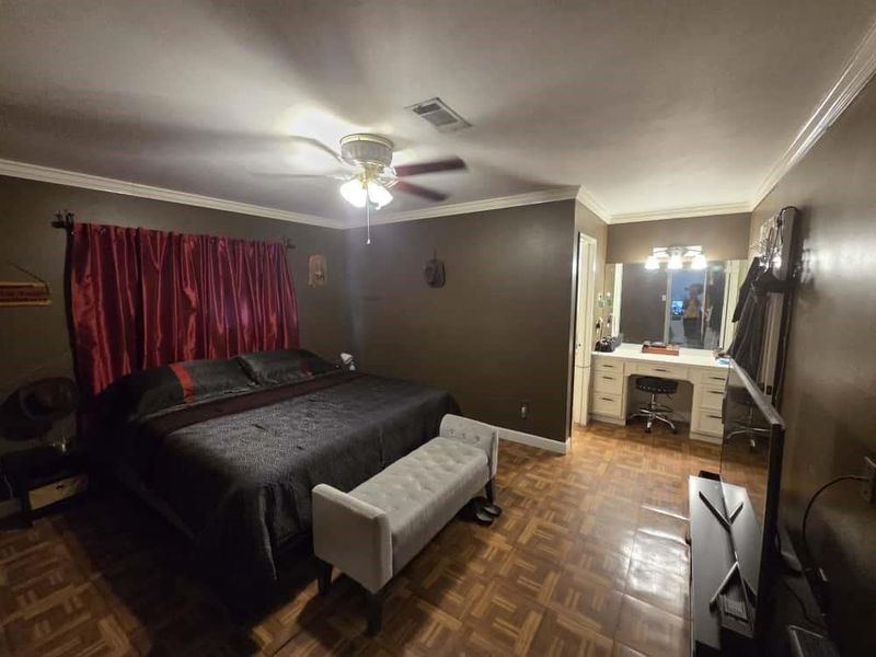 Bedroom featuring ornamental molding, a desk, a ceiling fan, and connected bathroom Bedroom featuring ornamental molding, a desk, a ceiling fan, and connected bathroom