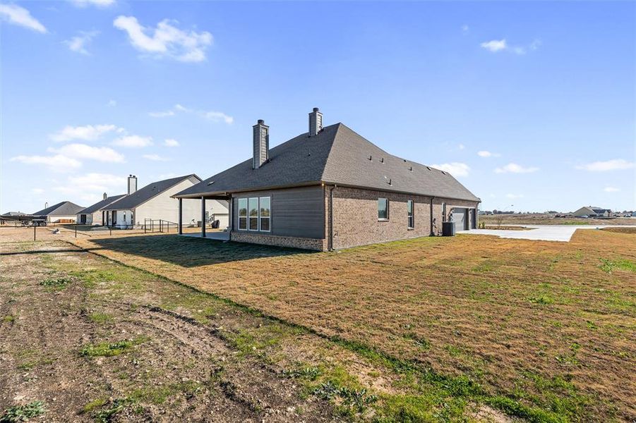 Rear view of property with a chimney, brick siding, a patio, and an attached garage