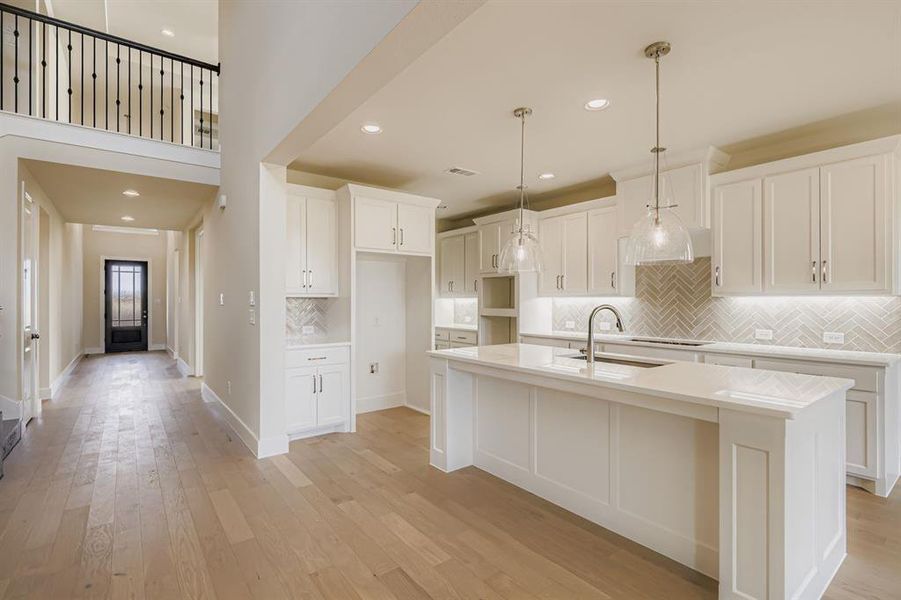 Kitchen with decorative backsplash, light wood-type flooring, hanging light fixtures, white cabinetry, and recessed lighting Kitchen with decorative backsplash, light wood-type flooring, hanging light fixtures, white cabinetry, and recessed lighting
