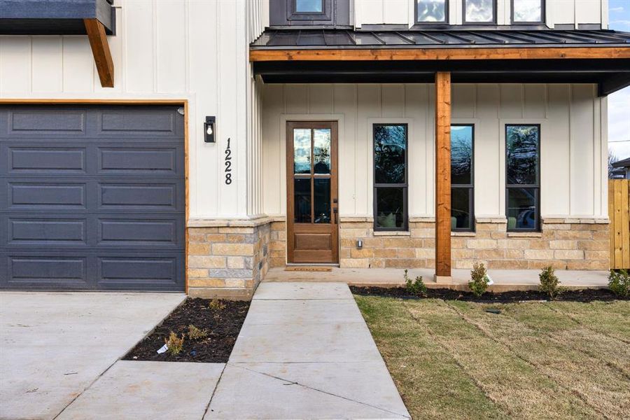 Doorway to property featuring a porch and a garage