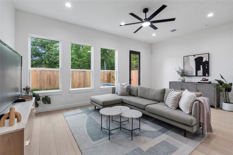 Open living area with clean lines, modern ceiling fan, and backyard access. Open living area with clean lines, modern ceiling fan, and backyard access.