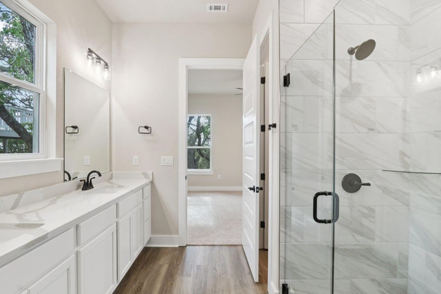 Primary ensuite bath featuring modern oversized walk-in shower with floor-to-ceiling tile and dual vanity with quartz countertops Primary ensuite bath featuring modern oversized walk-in shower with floor-to-ceiling tile and dual vanity with quartz countertops
