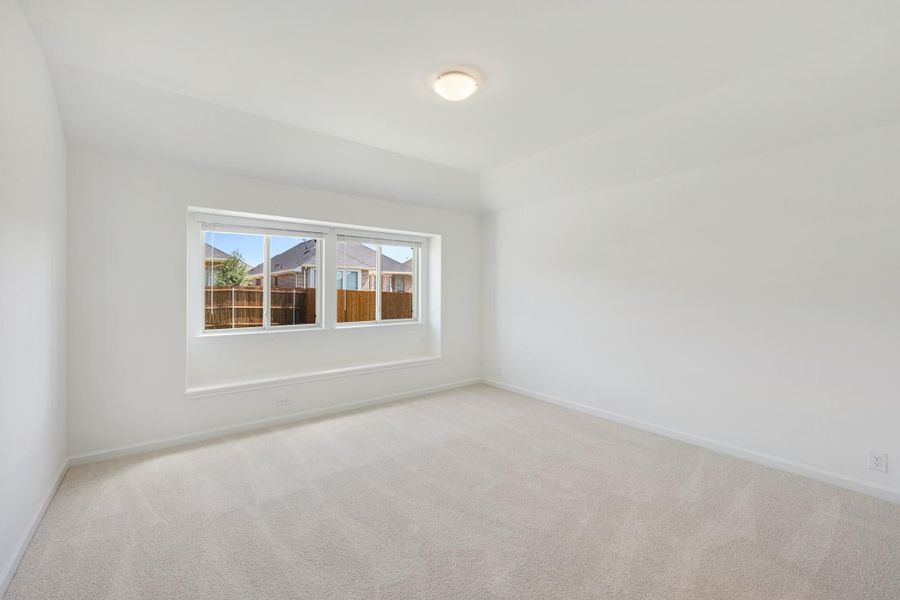 Empty bedroom with white walls, beige carpet, and a large window overlooking neighboring homes Empty bedroom with white walls, beige carpet, and a large window overlooking neighboring homes
