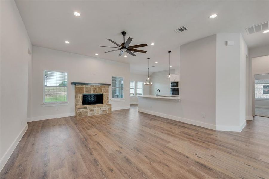 Unfurnished living room featuring sink, a fireplace, ceiling fan, and wood-type flooring