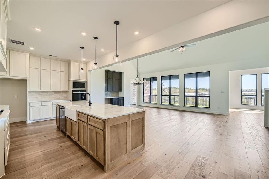 Kitchen featuring sink, light stone countertops, white cabinets, appliances with stainless steel finishes, and a spacious island