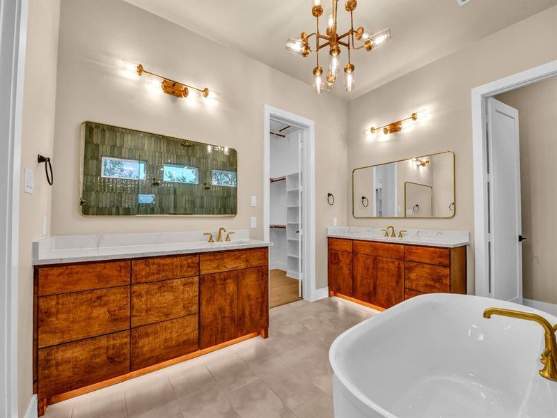 Bathroom with a bath, vanity, and a chandelier