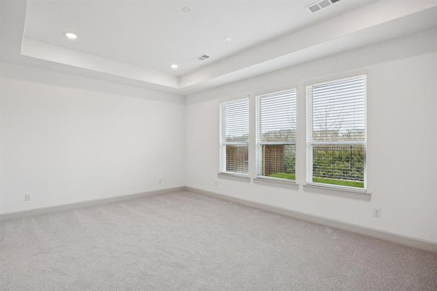 Peaceful and relaxing, this owners suite features high ceilings, large windows and plush carpeting in a neutral color palette.