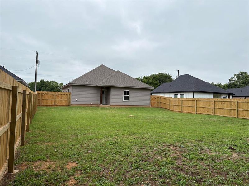 Rear view of house featuring a fenced backyard and roof with shingles Rear view of house featuring a fenced backyard and roof with shingles