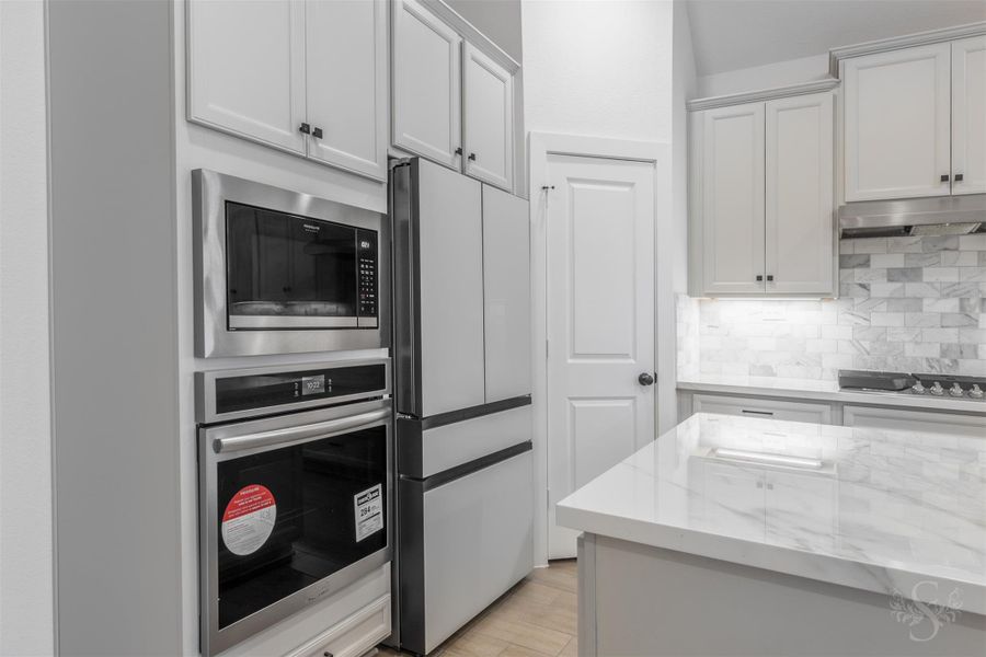 Premium built-in appliances, including a modern microwave/oven stack and sleek panel-front refrigerator, bring both beauty and efficiency to the kitchen. Clean lines and polished finishes enhance the home's contemporary appeal. Premium built-in appliances, including a modern microwave/oven stack and sleek panel-front refrigerator, bring both beauty and efficiency to the kitchen. Clean lines and polished finishes enhance the home's contemporary appeal.