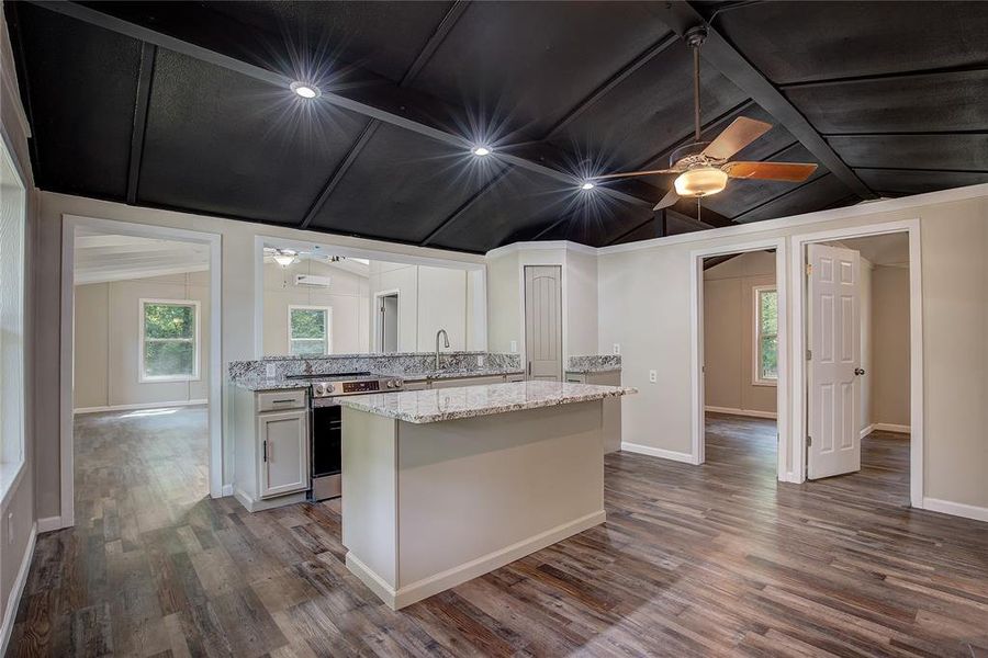 Kitchen with electric range, light stone countertops, ceiling fan, dark wood-type flooring, and white cabinets