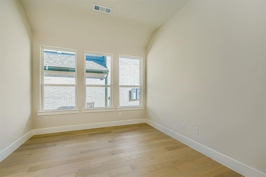 Empty room featuring light wood finished floors and lofted ceiling