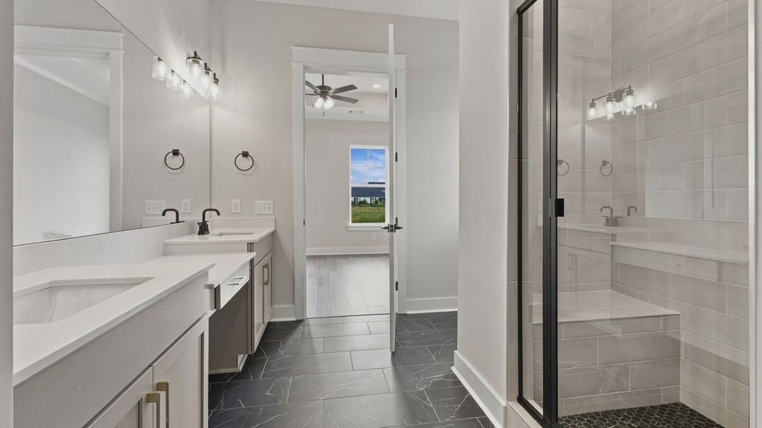 Closet view of bathroom showing spacious walk-in shower and dual sinks.
