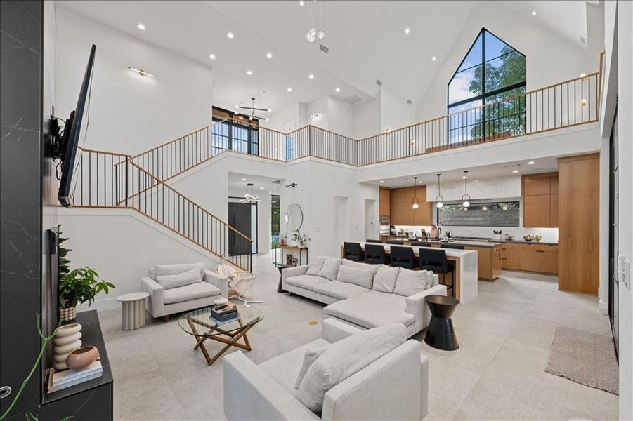 Living area with high vaulted ceiling, recessed lighting, and stairs