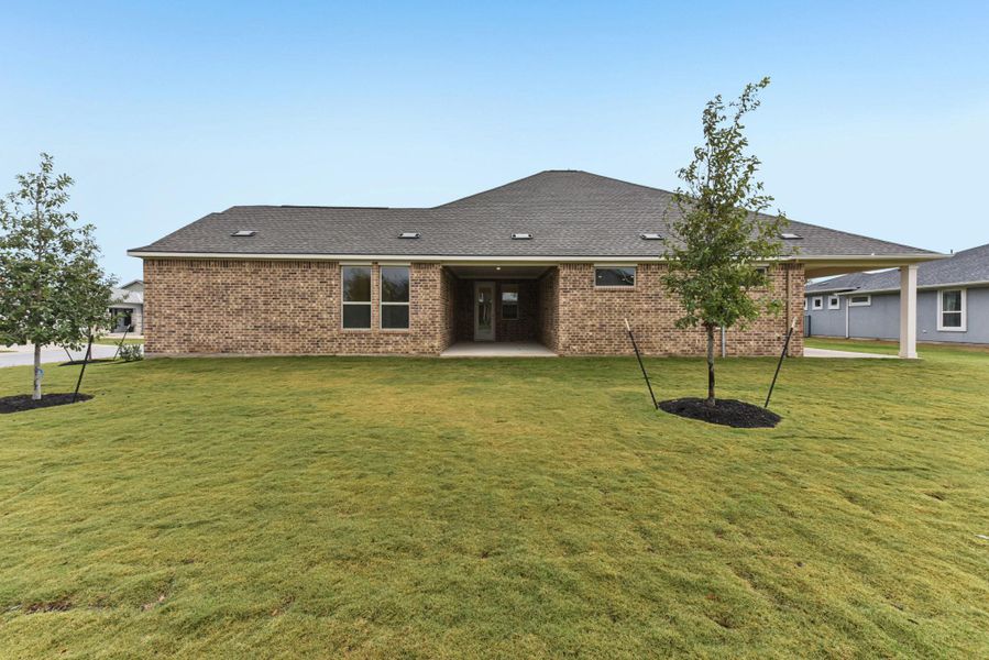 Back of house with a patio, a lawn, and brick siding