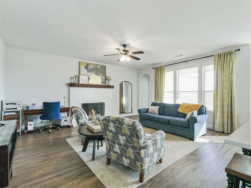 Living room featuring a brick fireplace, hardwood / wood-style floors, and ceiling fan