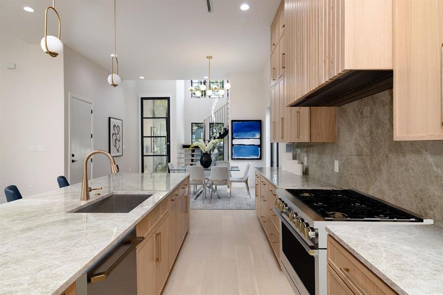 Kitchen featuring light brown cabinets, high end stove, sink, and dishwashing machine