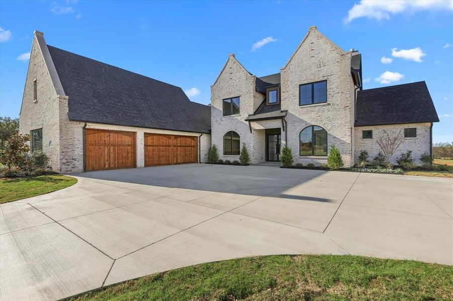 French provincial home with brick siding, driveway, a shingled roof, and a garage