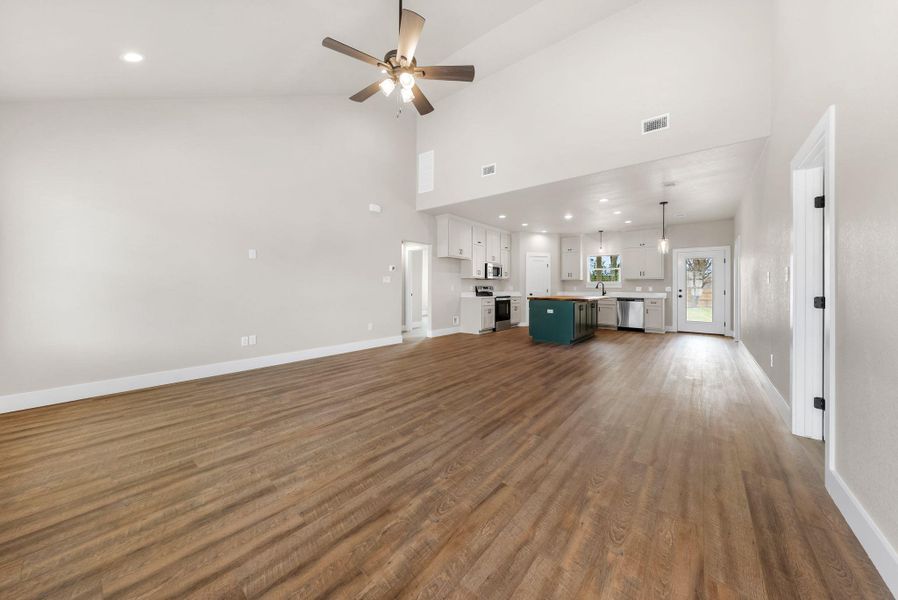 Unfurnished living room featuring recessed lighting, ceiling fan, dark wood-style flooring, and a high ceiling