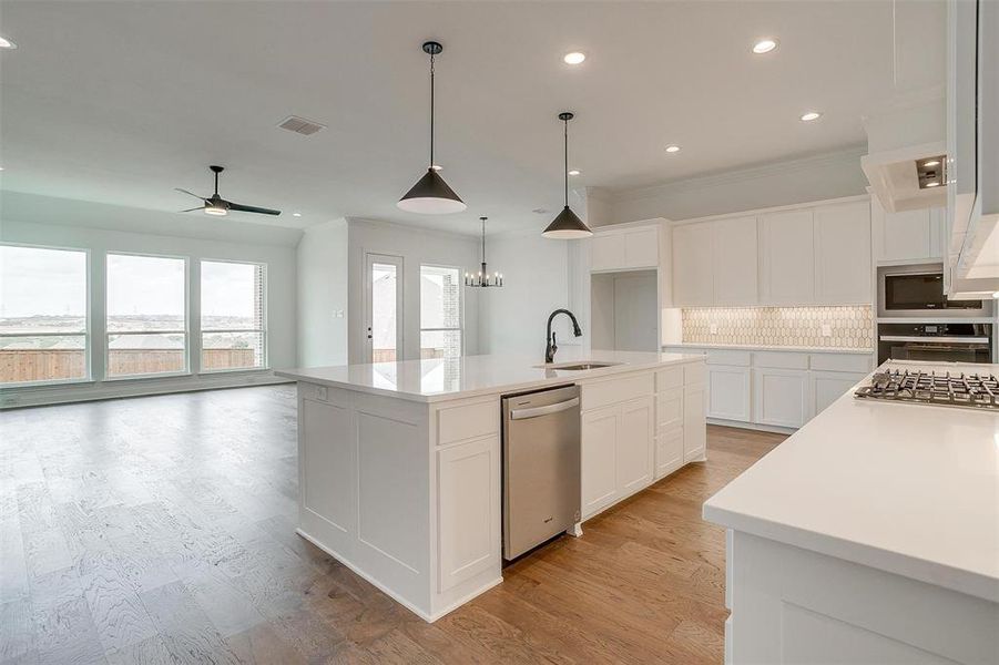 Kitchen featuring light wood-type flooring, sink, stainless steel appliances, an island with sink, and white cabinets