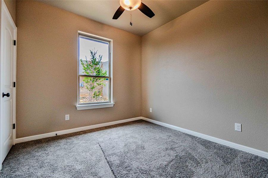 Carpeted empty room featuring ceiling fan