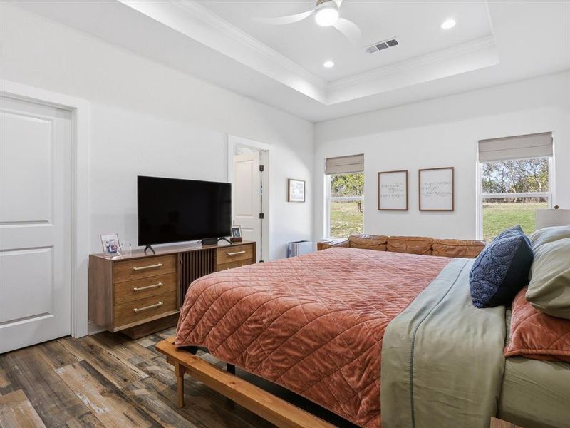 Bedroom featuring ornamental molding, a tray ceiling, dark wood-style flooring, recessed lighting, and a ceiling fan