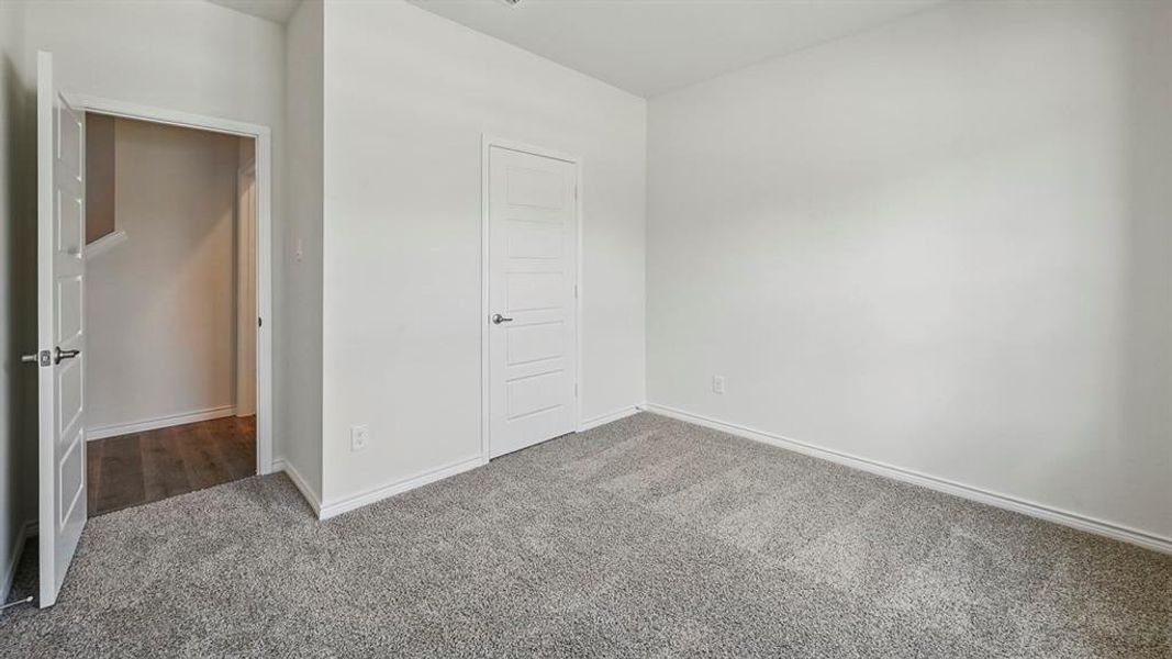 Carpeted room with a modern paneled door, offering neutral wall tones and recessed lighting Carpeted room with a modern paneled door, offering neutral wall tones and recessed lighting