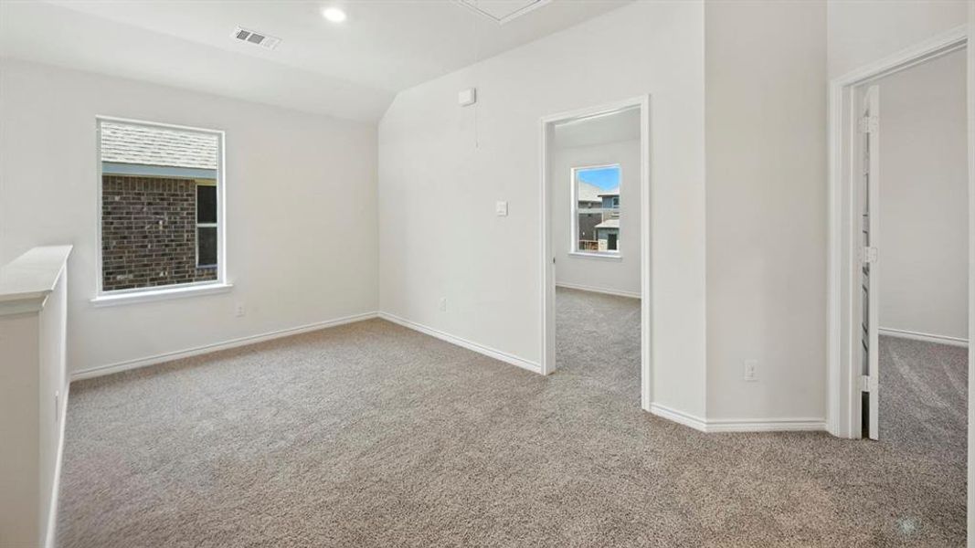 Unfurnished room featuring light colored carpet, healthy amount of natural light, lofted ceiling, attic access, and recessed lighting