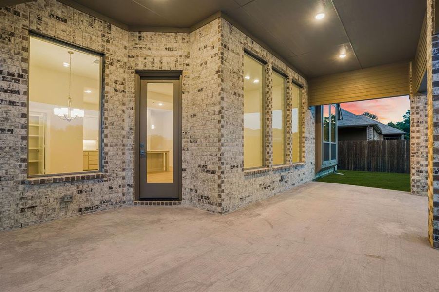 Property entrance featuring a patio, brick siding, and fence Property entrance featuring a patio, brick siding, and fence