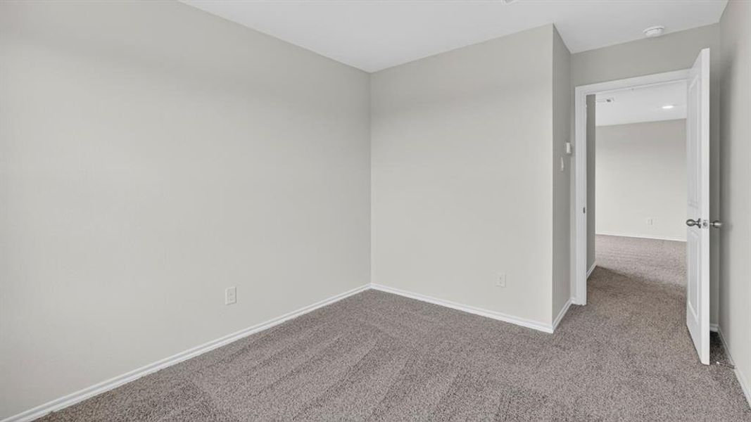 Neutral-toned room featuring light gray walls, dark gray carpet, and white baseboards Neutral-toned room featuring light gray walls, dark gray carpet, and white baseboards