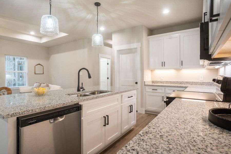 Kitchen featuring dishwasher, a sink, electric range, light wood-style flooring, and white cabinetry