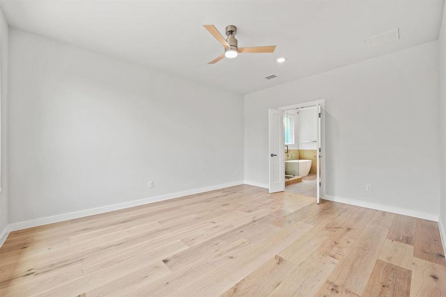 Unfurnished bedroom with light hardwood / wood-style floors, ensuite bathroom, and ceiling fan