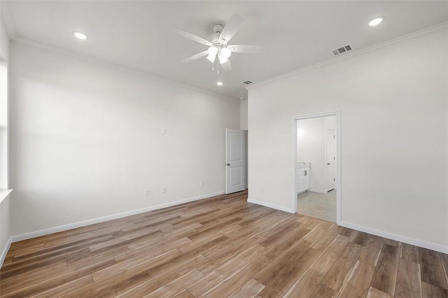 Unfurnished bedroom featuring ornamental molding, light wood finished floors, a ceiling fan, recessed lighting, and connected bathroom