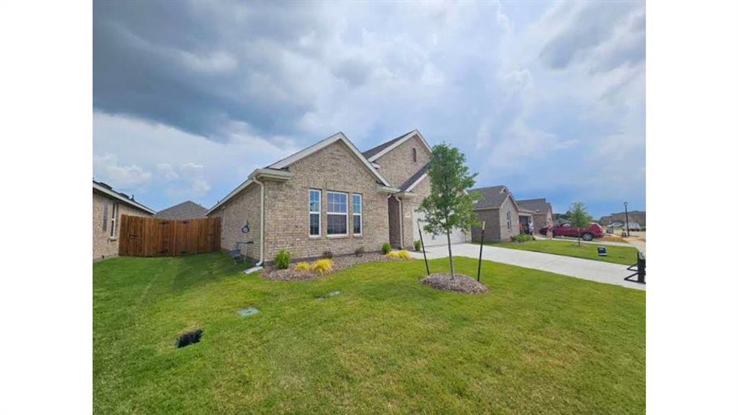 Brick exterior featuring an attached garage, landscaped front yard, and a concrete driveway