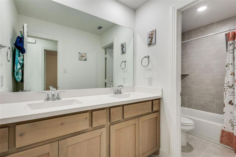 Full bath featuring double vanity, light tile patterned floors, shower / tub combo, and recessed lighting Full bath featuring double vanity, light tile patterned floors, shower / tub combo, and recessed lighting