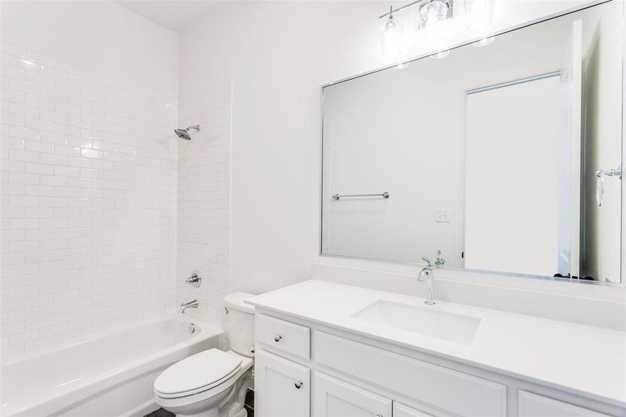 Full bathroom with tiled shower / bath combo, toilet, and vanity